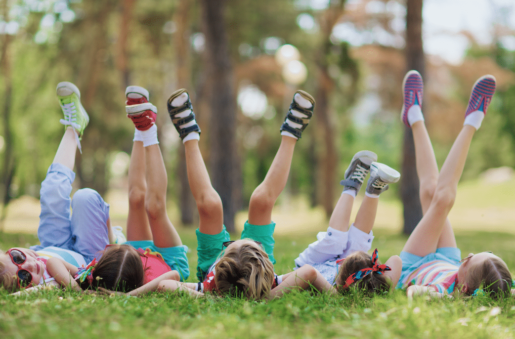 Kids laying on the lawn with their hands behind their heads and their feet up in the air. Getting you lawn ready for fall is important. Watson' Weed Control can help.